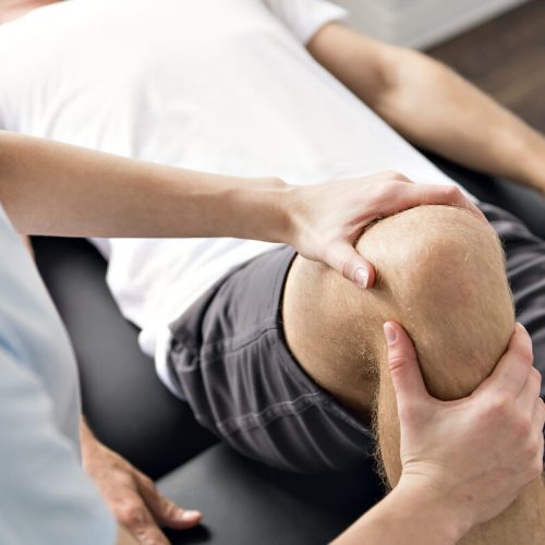 A Patient at the physiotherapy doing physical exercises with his therapist